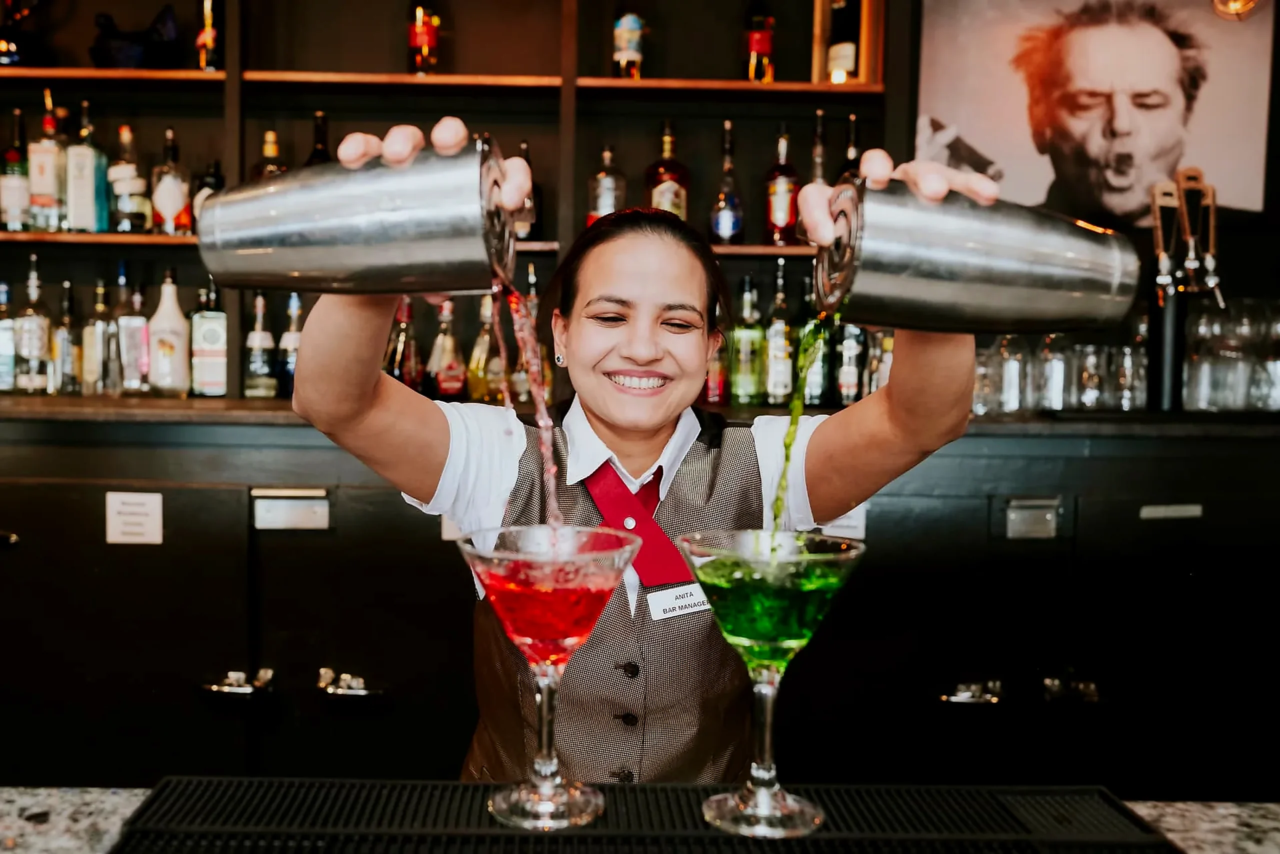 Bar manager pouring two cocktails behind the bar at the Wabush Hotel