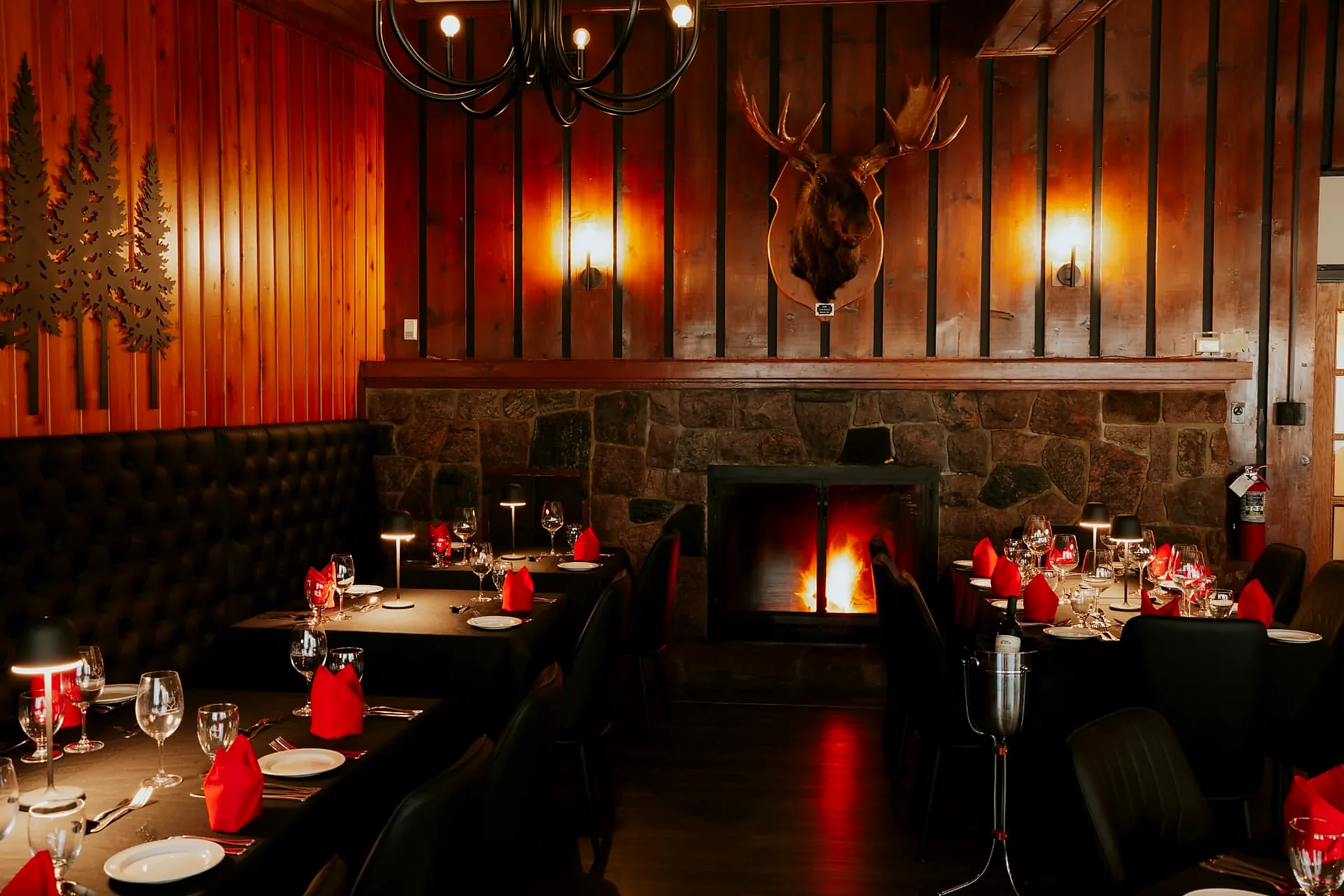 Dining room tables beside the lit stone fireplace at the Frozen Rooster