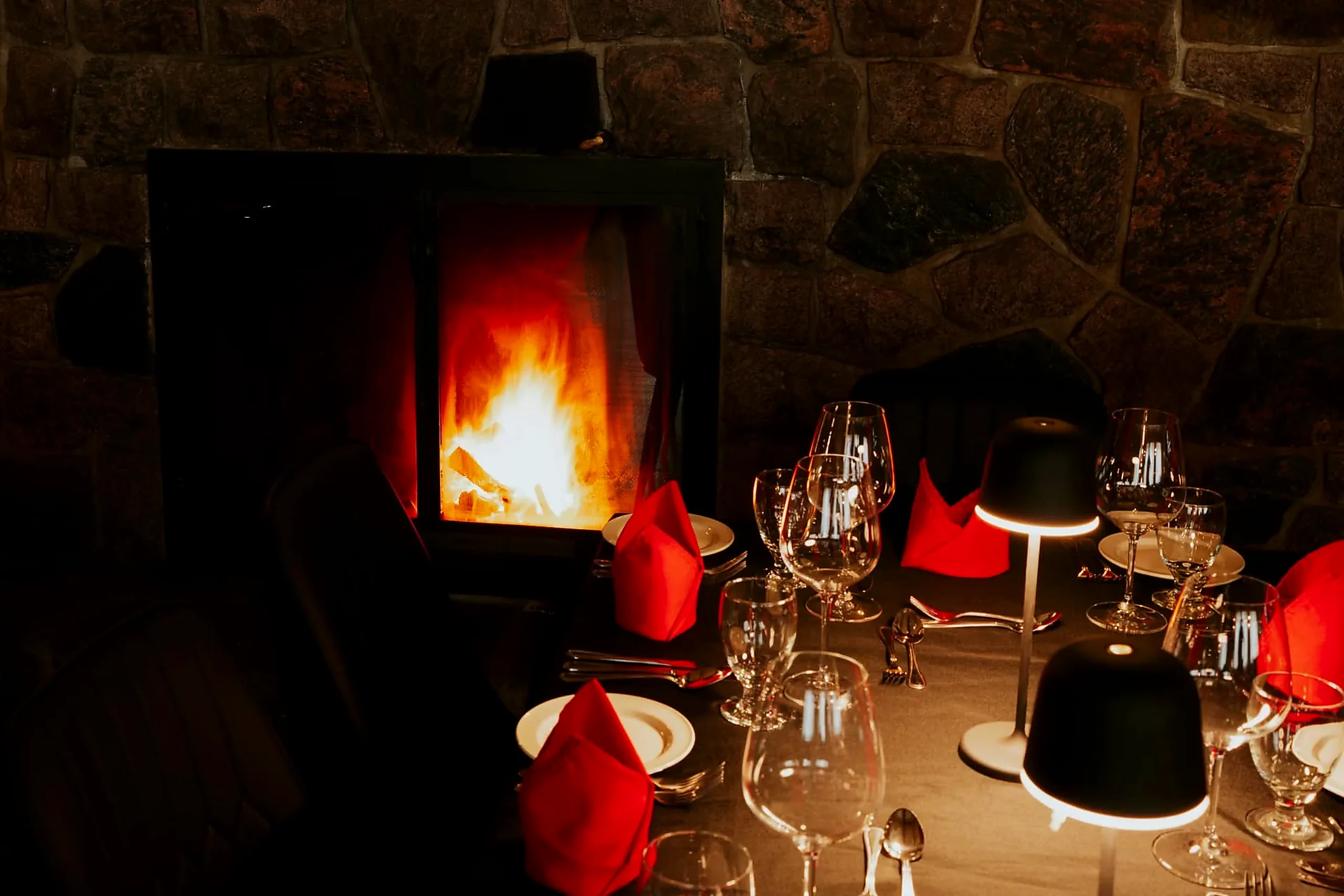 Table set with red napkins directly in front of the restaurant fireplace