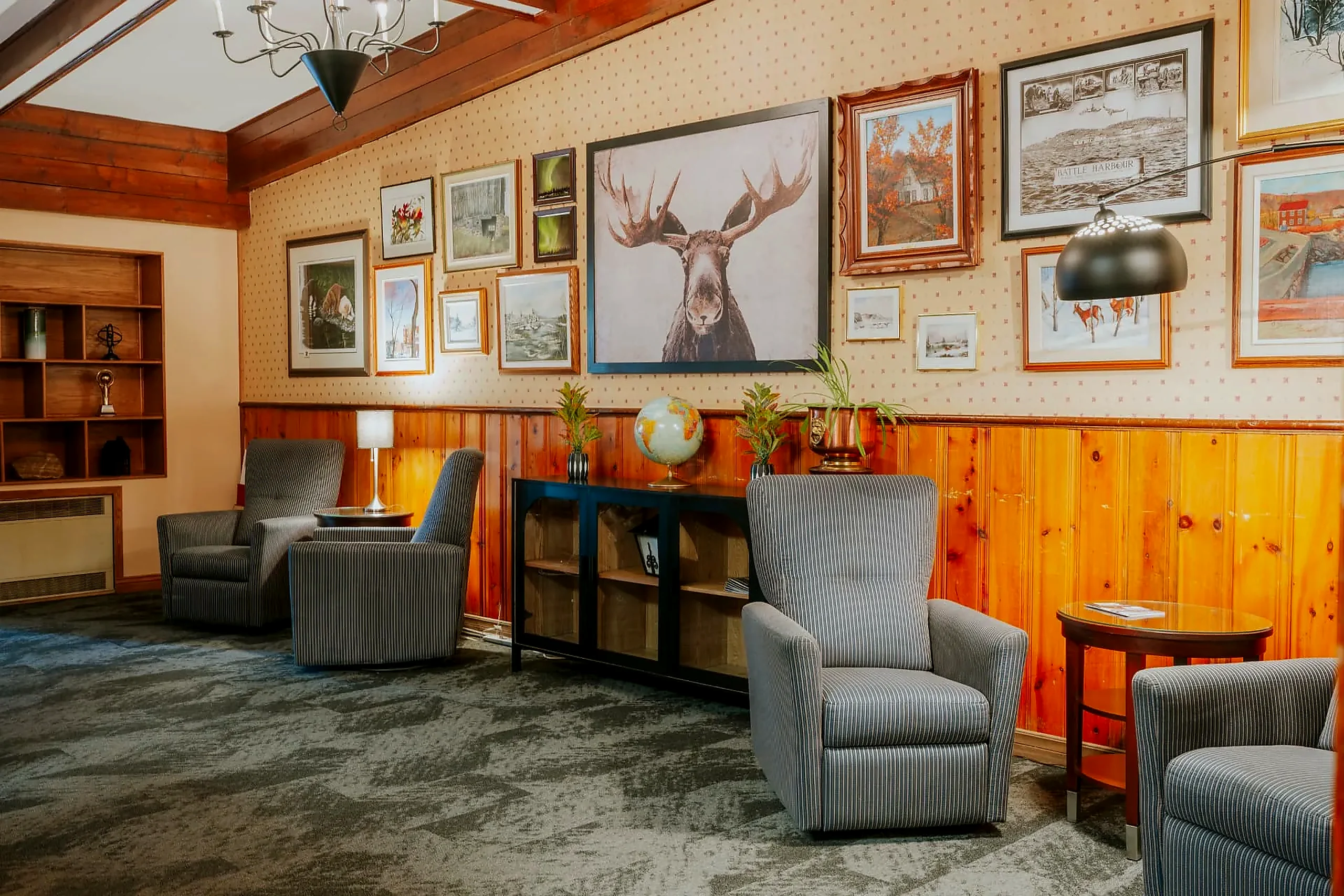 The Wabush Hotel guest lounge with pine panelling, armchairs and framed local artwork