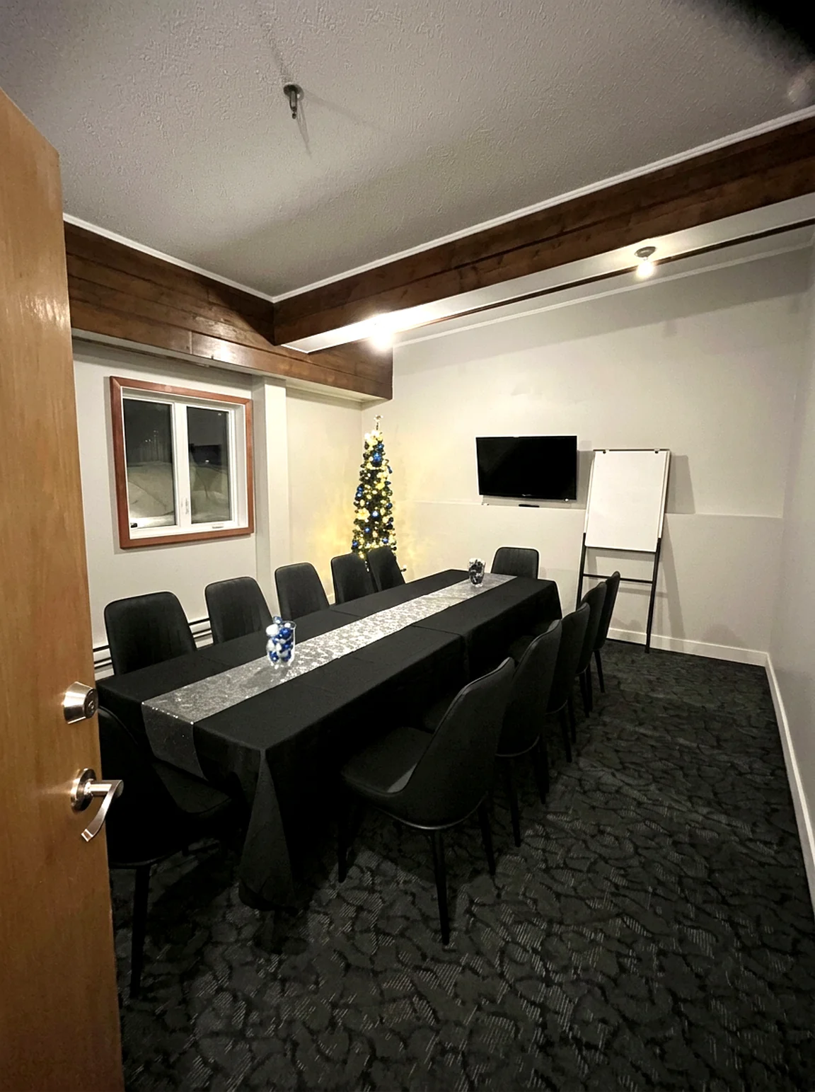 The small meeting room at the Wabush Hotel set as a boardroom with a wall-mounted TV and flip chart