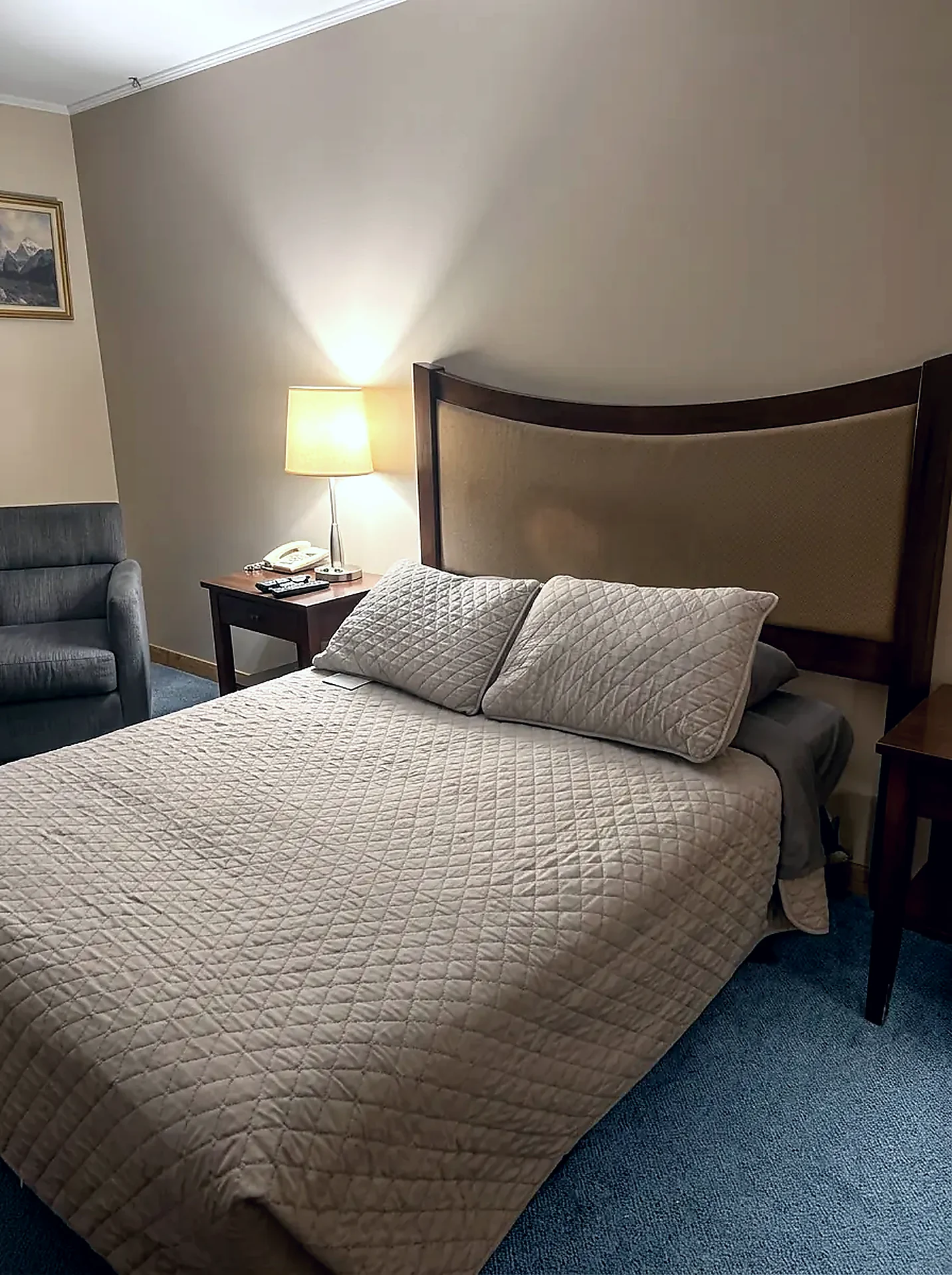 Standard guest room at the Wabush Hotel with one double bed, bedside lamp and an armchair