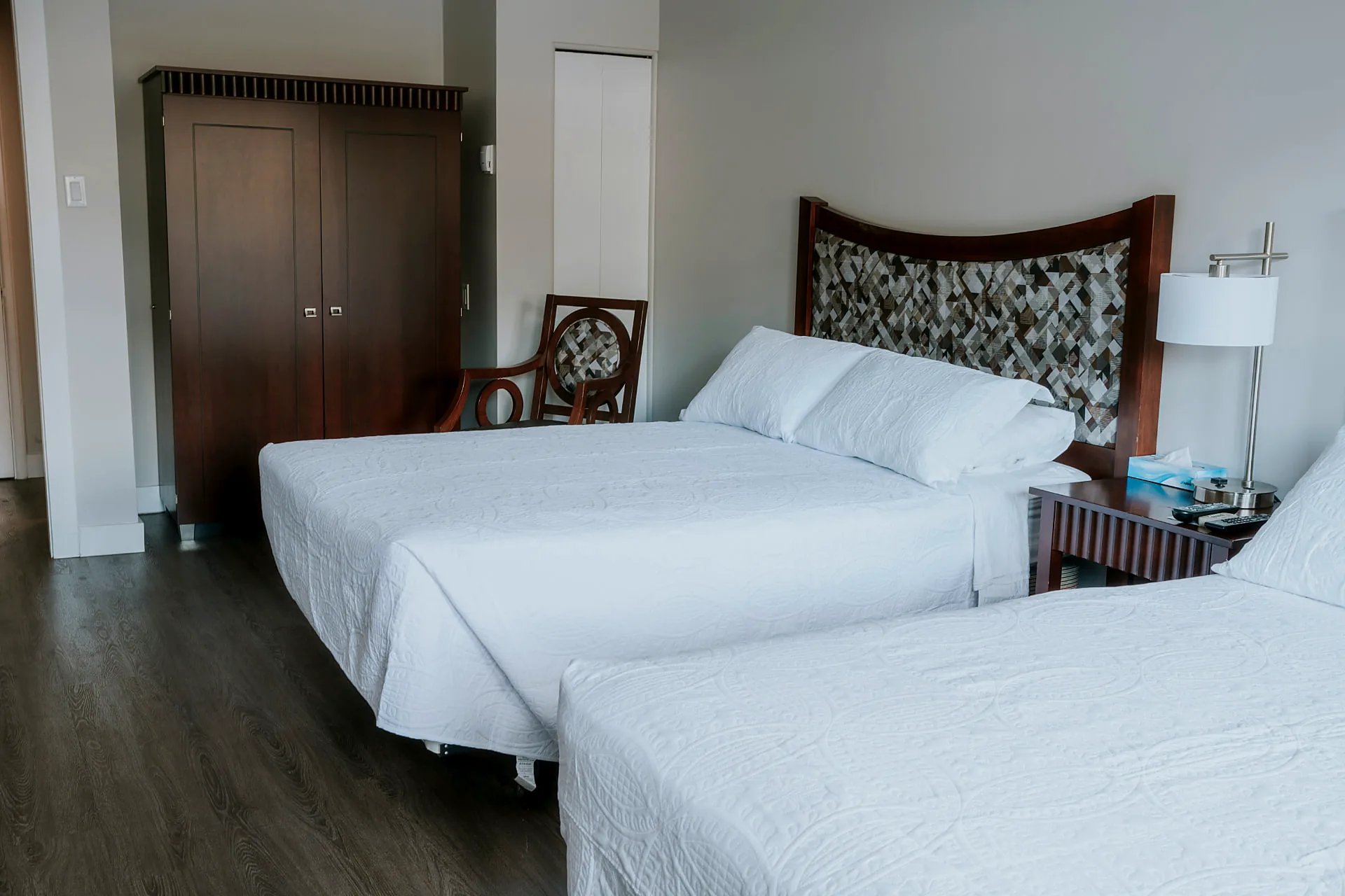 Renovated Wabush Hotel guest room with two double beds, white bedding, a carved wood headboard and a window